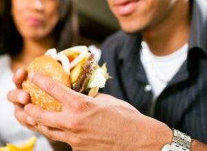 man eating burger while woman watches