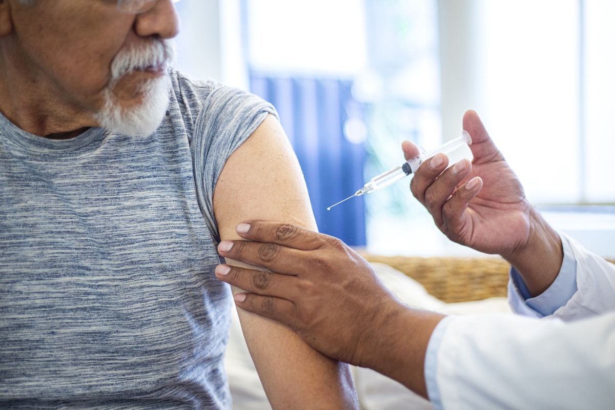 doctor injecting older man with vaccine