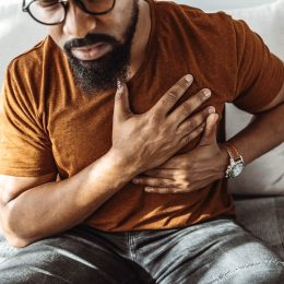 man holding his chest in pain indoors.