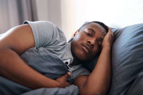 Fotografie cu un tânăr frumos întins în pat simțindu-se deprimat și singur acasă