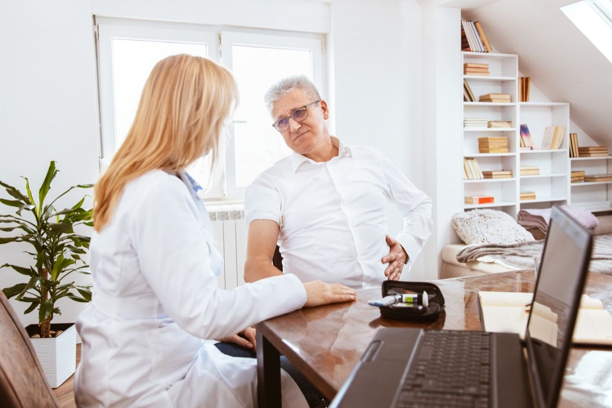 Middle-aged man being examined by a female doctor in a doctor's office. Patient complains to the doctor of pancreas pain.