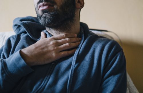 Young adult man suffering from sore throat