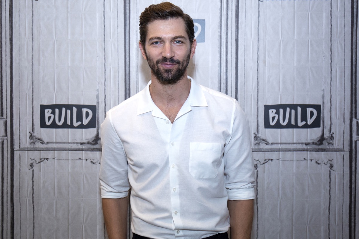 michiel huisman in white button down in front of build step and repeat