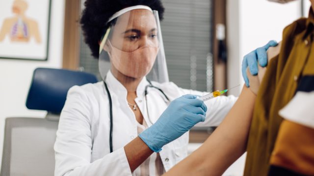 female doctor giving a Covid-19 vaccine to a young woman.
