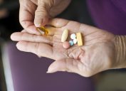 A senior person's hands holding supplement pills