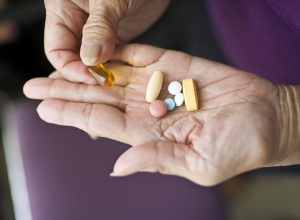 A senior person's hands holding supplement pills