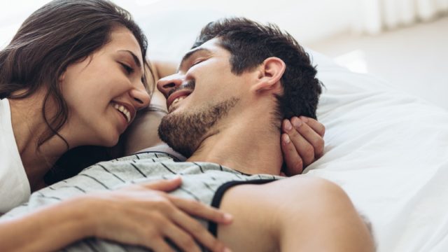 young couple smiling at each other under the sheets