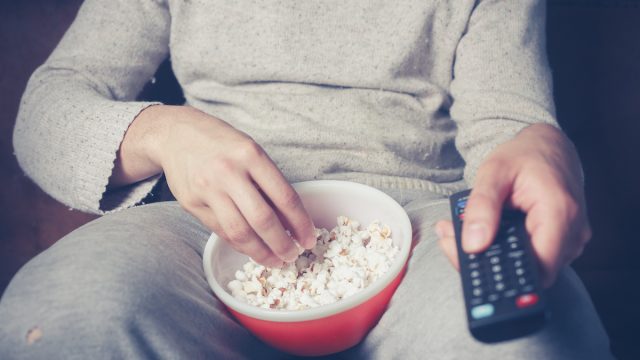 Man watching tv with popcorn and remote
