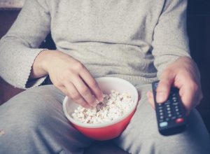Man watching tv with popcorn and remote