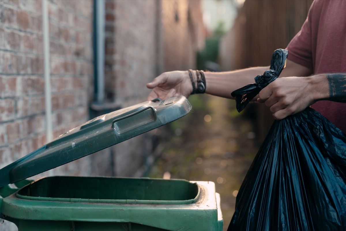 person throwing trash in outdoor bin