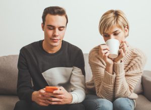 Jealous girl spying her boyfriend's mobile phone while he typing a message
