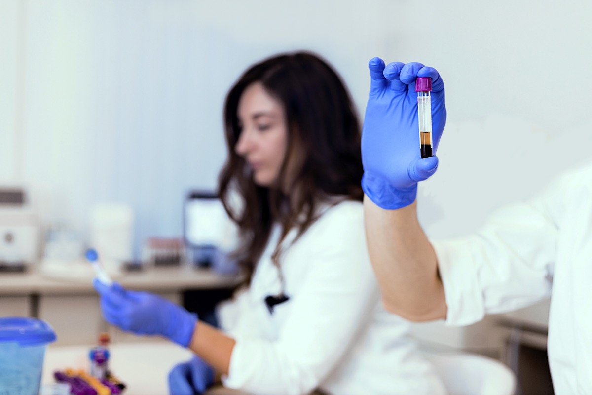 Hand of a lab technician holding blood tube test. Health care researchers working in life science laboratory. Doctor holds a blood sample tube in his hand testing in the laboratory