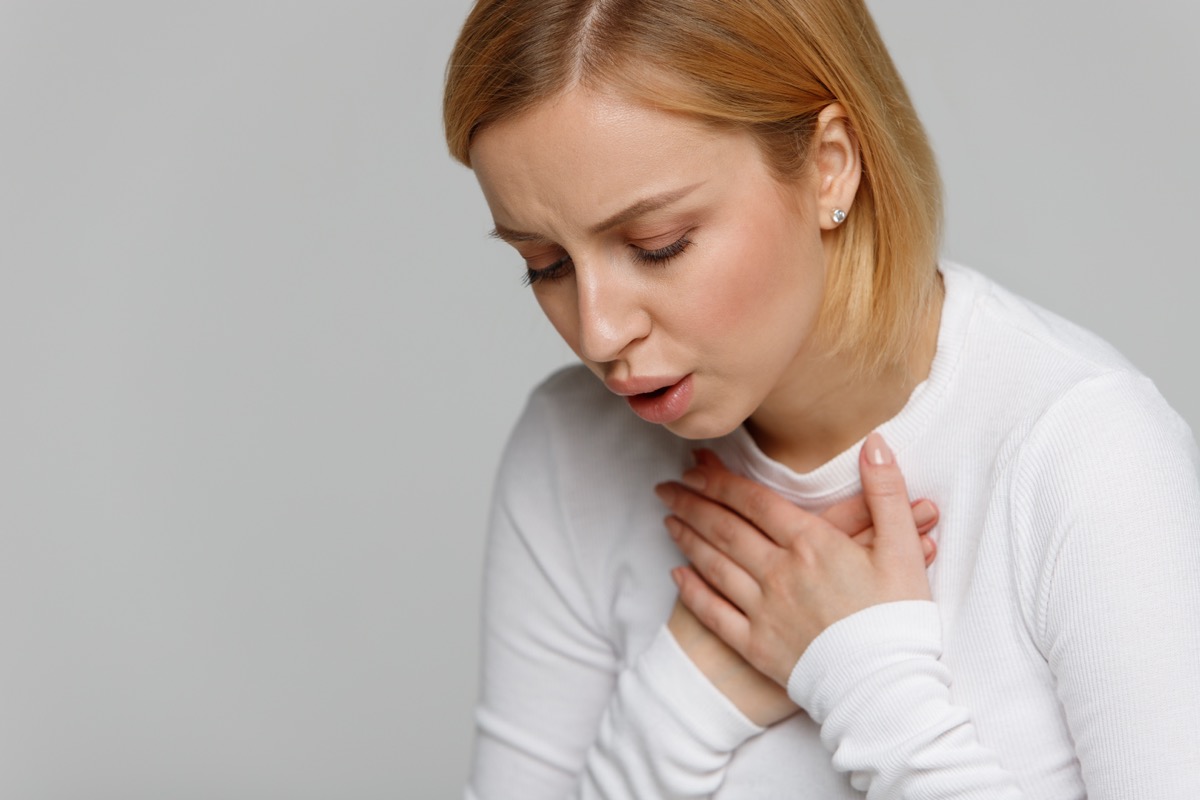 woman breathing, holding her chest, lung pain