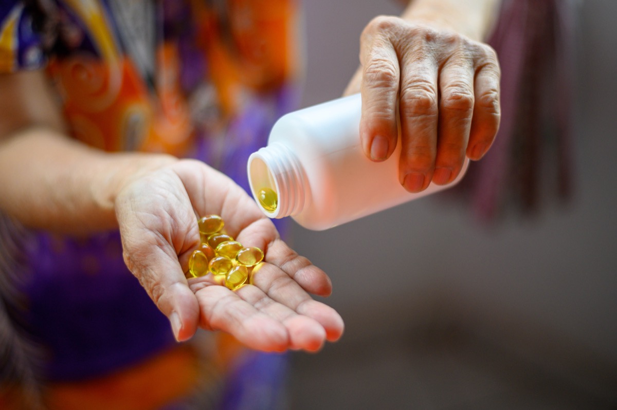 Image of Bottle of omega 3 fish oil capsules pouring into hand.