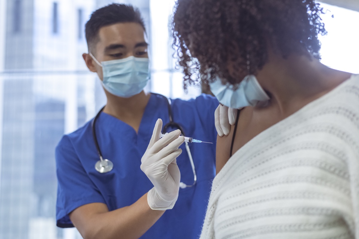 Shot of a male nurse wearing blue medical scrubs, giving vaccine