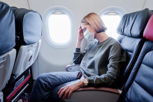 woman sitting on a plane with facemask