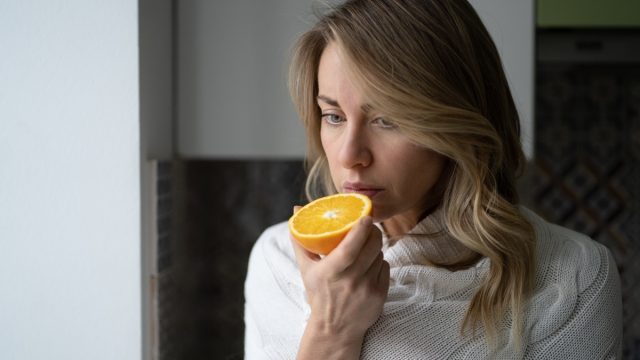 woman trying to smell half an orange