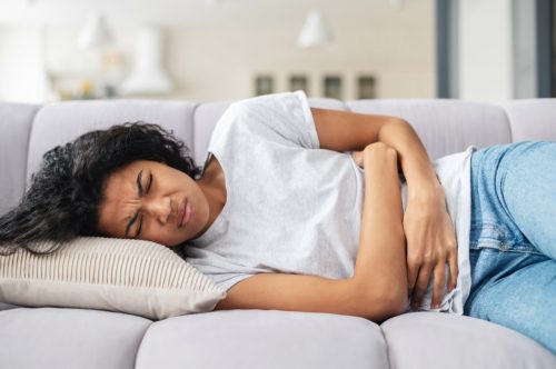 woman lying on couch with stomach cramps