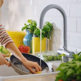 A woman washing dishes in the kitchen sink