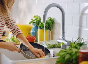 A woman washing dishes in the kitchen sink