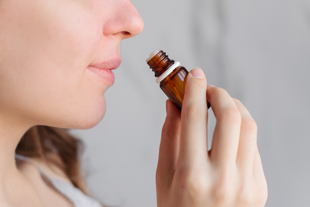 A young woman smell a bottle of essential oils