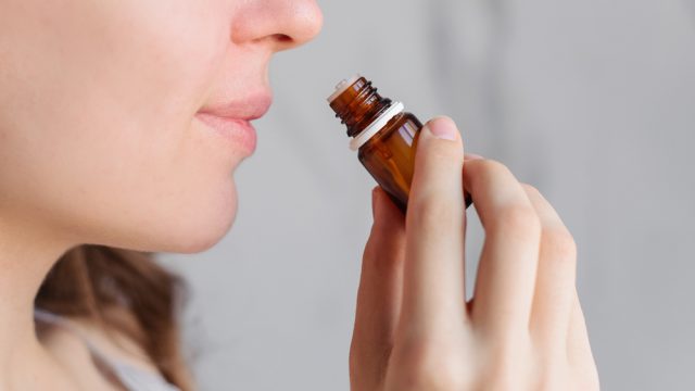 A young woman smell a bottle of essential oils