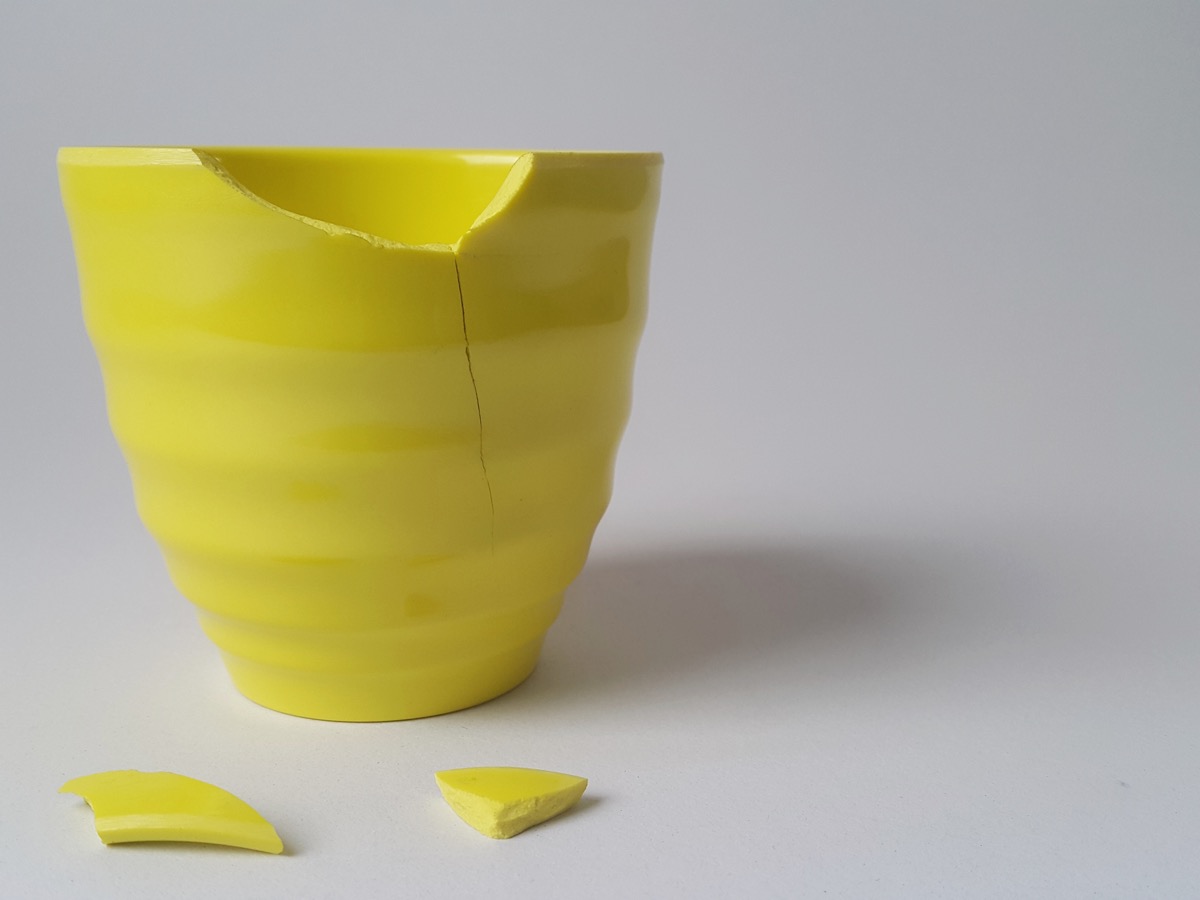 broken yellow cup on white background