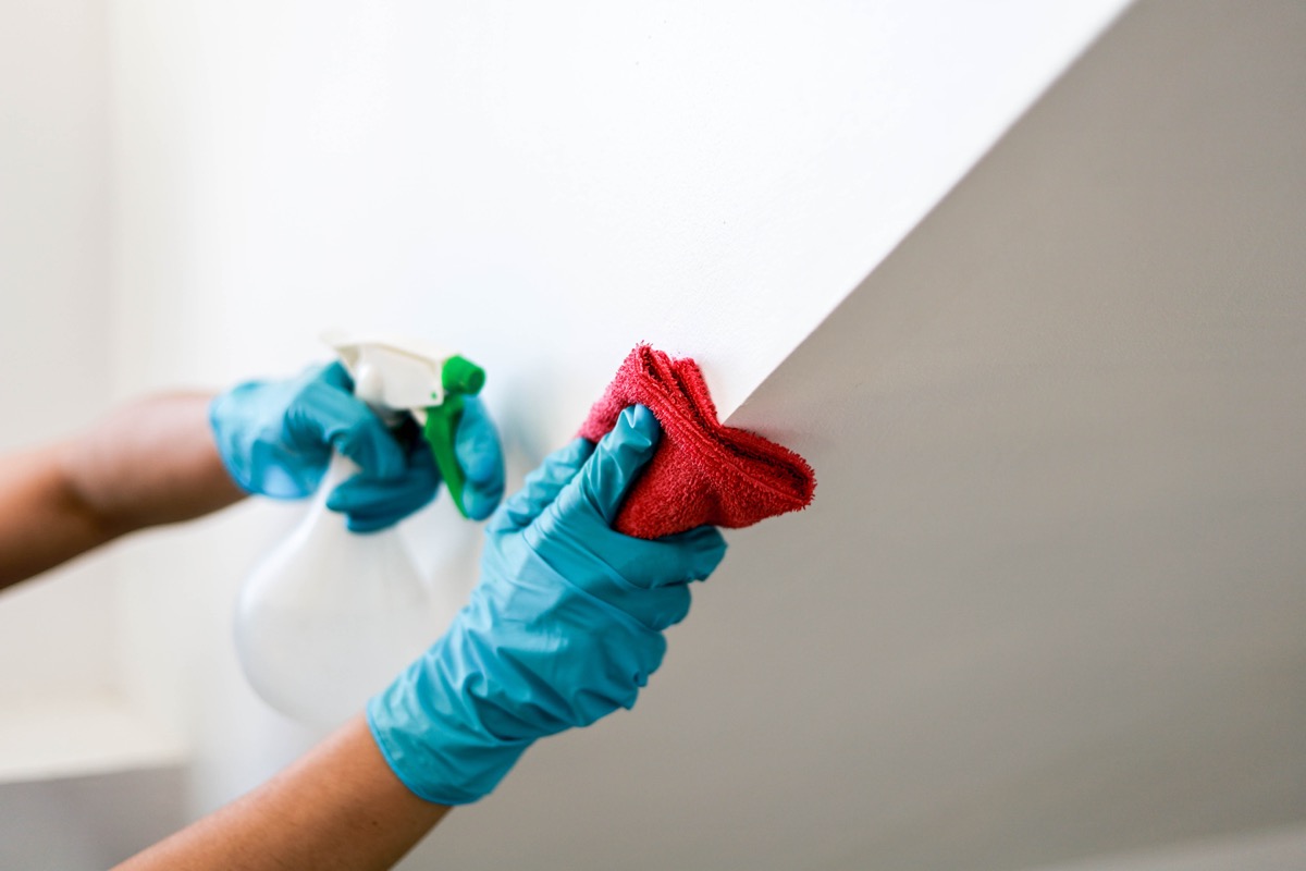 person wearing gloves cleaning wall