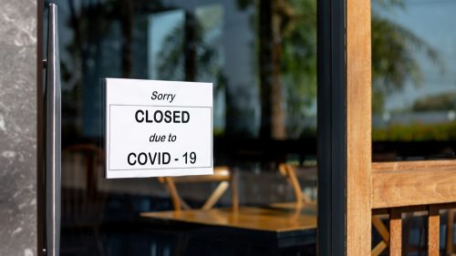 A closed sign hanging on the front of a business due to COVID-19 lockdowns