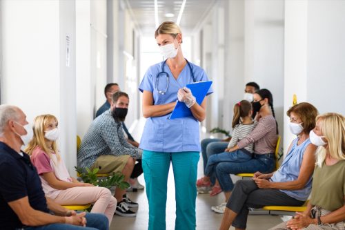young blonde doctor walking through crowded waiting room