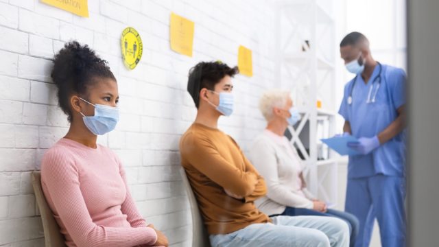 people sitting in doctor's office waiting room wearing masks amid covid