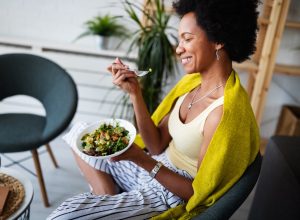 woman, sitting with bowl of salad, eating, smiling