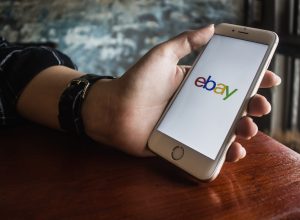 Hand holding iPhone with eBay app on the screen
