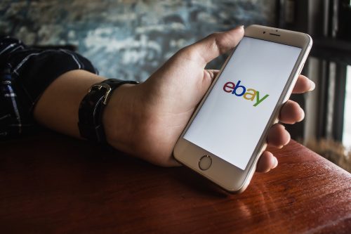 Hand holding iPhone with eBay app on the screen