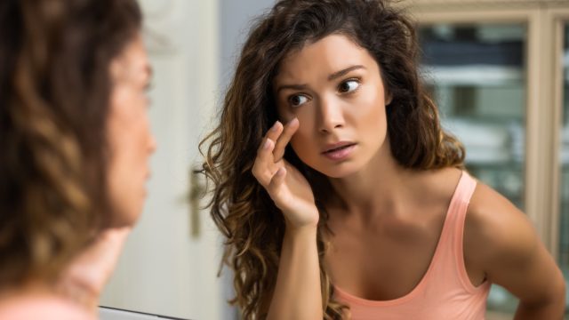 woman looking in a mirror at her eyes