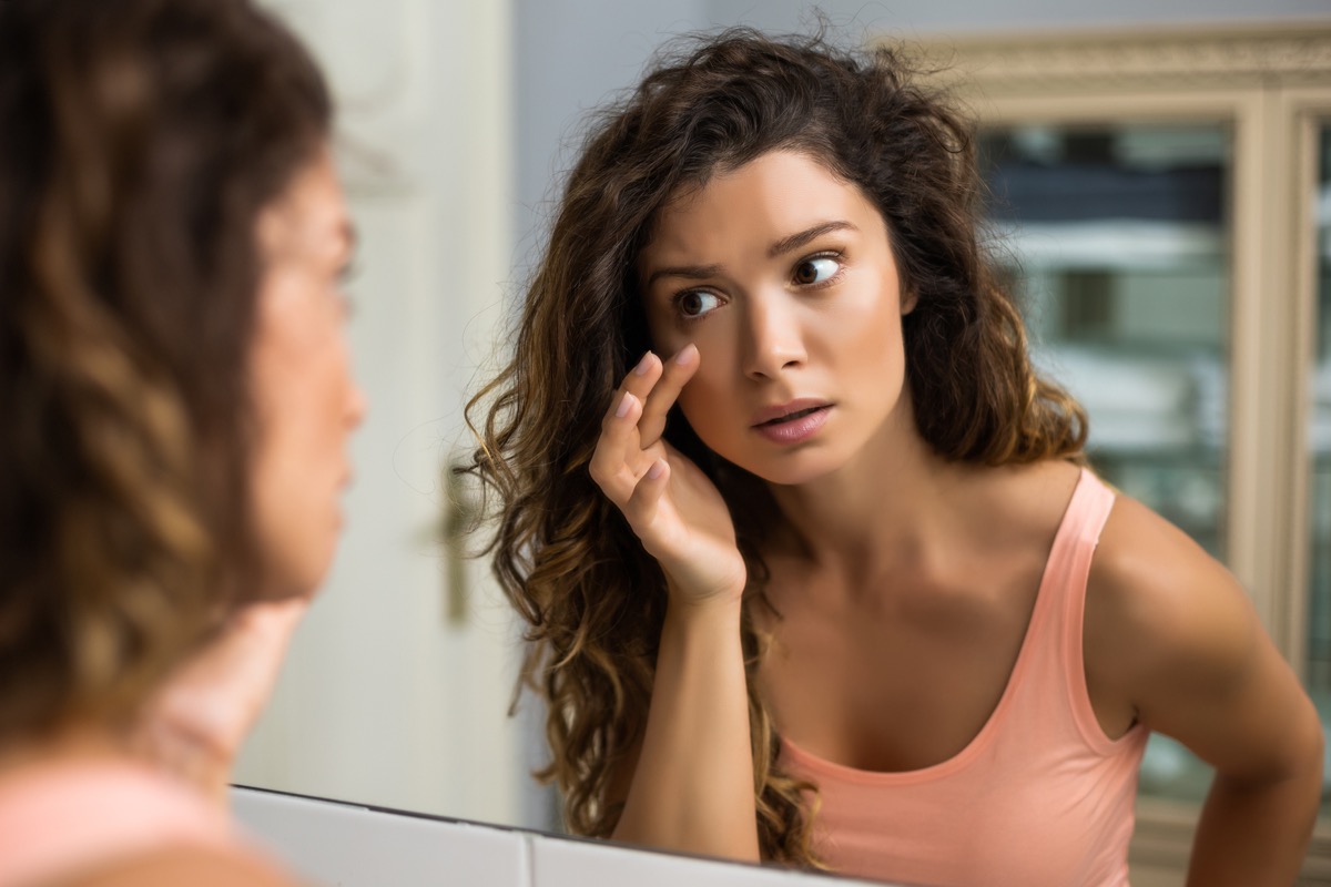 woman looking in a mirror at her eyes