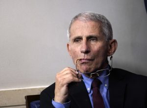 fauci holds his glasses to his face during a covid briefing