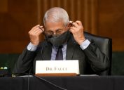 Dr. Anthony Fauci putting on a face mask after speaking to the Senate Health Committee