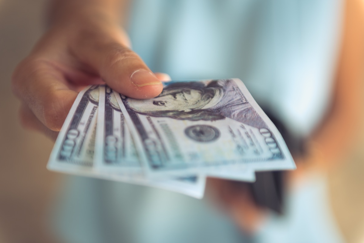 Mână ținând bancnote de o sută de dolari din moneda Statelor Unite