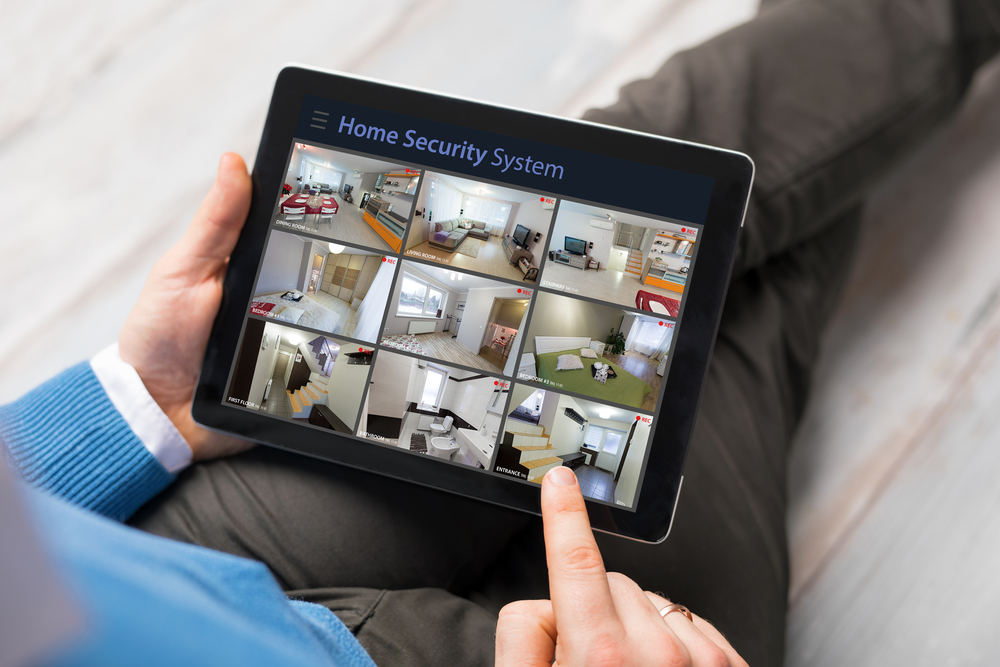 A person using a tablet to check the video feeds from their home security camera system