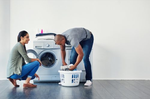 Photo of a young woman doing laundry at home