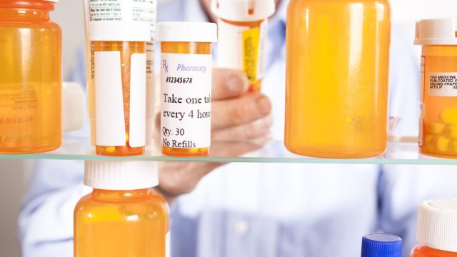 Senior adult man gets prescription medicines out of his medicine cabinet.