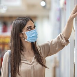 Young woman shopping in a grocery store and wearing protective medical mask. Women with face mask for protection against influenza virus shopping. Shopping in supermarket