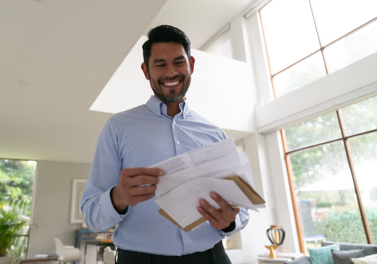 Handsome man at home going over his mail smiling very happy - Low angle view