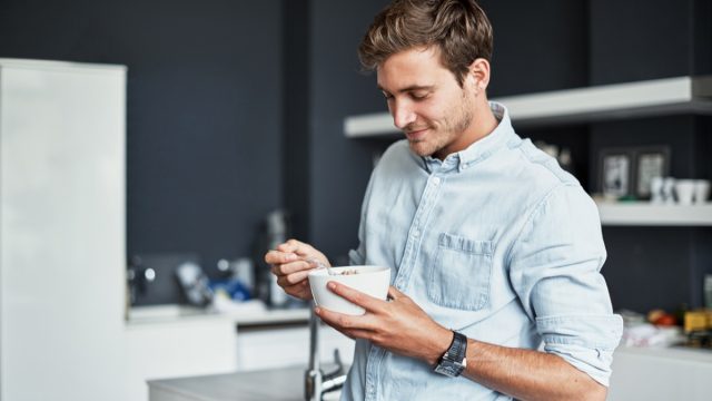 young man eating food out of a bowl