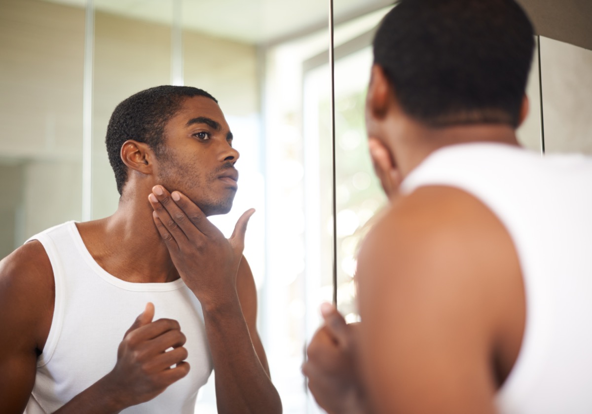 A young man applying moisturizer to his face