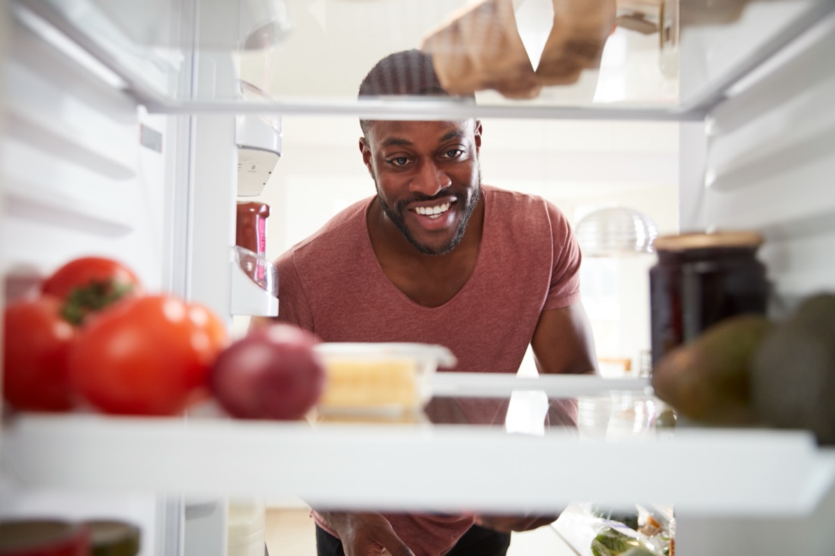 Man opening fridge and looking inside