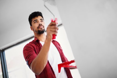 Low angle view of young man painting wall in his apartment.