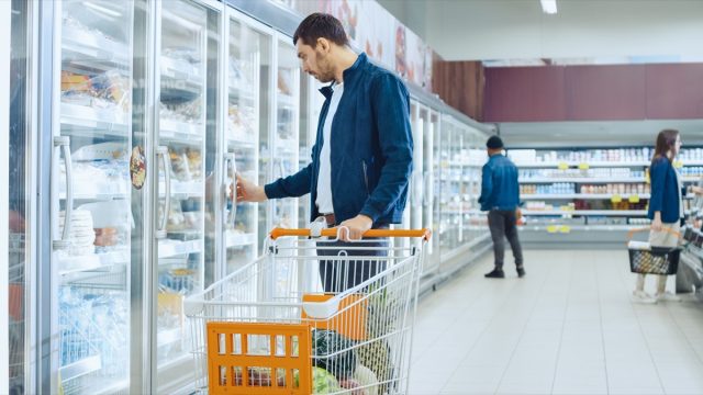 man shopping in the frozen foods section of a supermarket