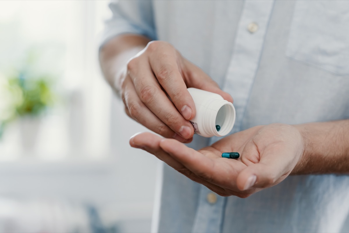 Capsule in palm of hand. White pill bottle. Don't increase the dose. Using medicine against pain. Medical, healthcare and one step from death concept. Photo of Unidentified patient holding a pills. Unrecognizable Mature man spilling pills onto hand during the day at home.